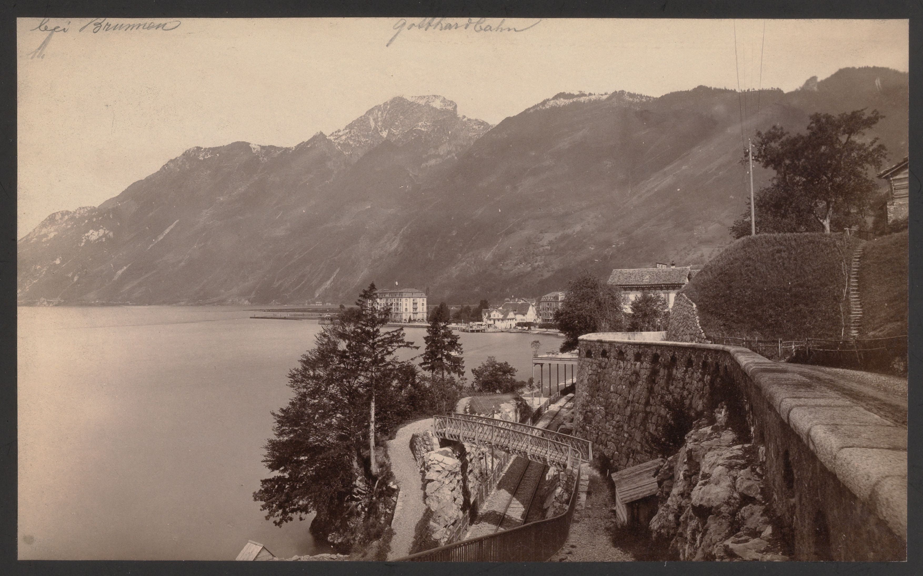 old photo of lakeside village, with train tracks in the foreground